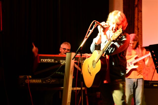 Helmut F. mit Gitarre und Band bei einem Liveauftritt